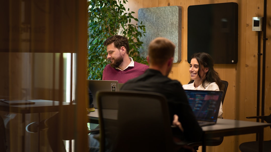 a group of people sitting around a table with laptops