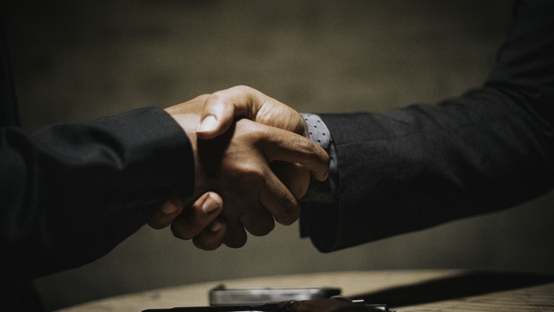 two people shaking hands over a wooden table