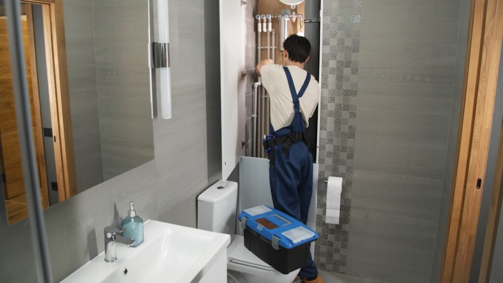 A plumber repairs plumbing in a bathroom.