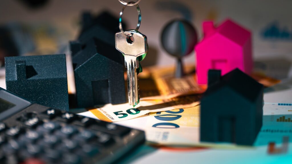 A calculator, keychain, and house model on a table