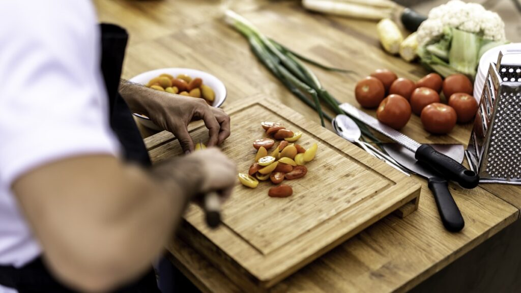 a person cutting up vegetables on a cutting board