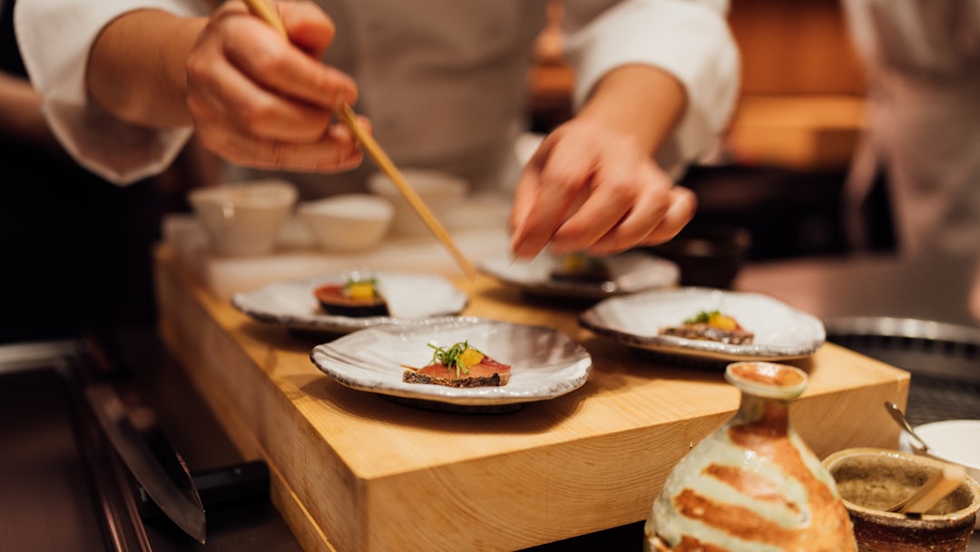 a person holding a chopstick over a plate of food