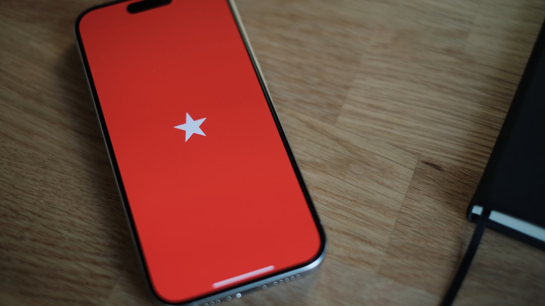 A red cell phone sitting on top of a wooden table