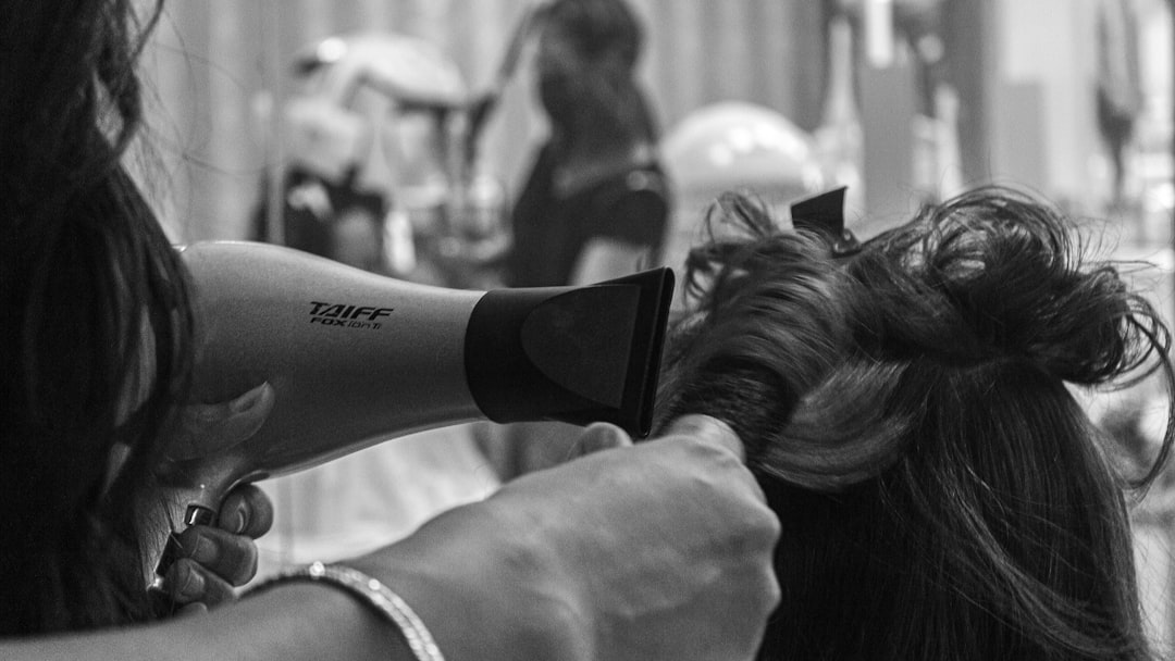 grayscale photo of woman holding hair blower