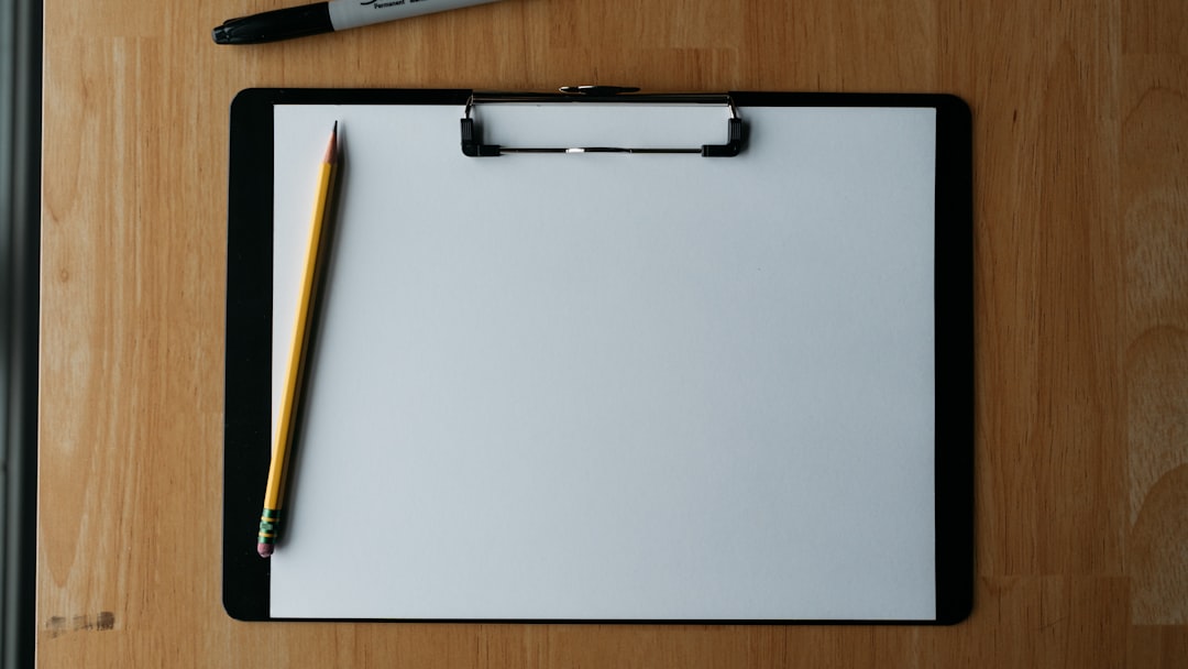 Clipboard, pencil, and pen on a wooden surface.
